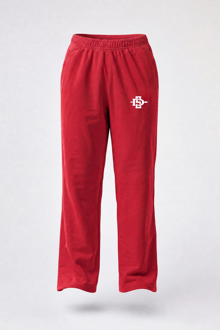 Red sweatpants with an elastic waistband and a small embroidered mascot logo on the left thigh, shown against a light gray background.