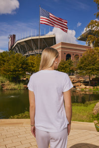 woman wearing white tee in front of a pond and stadium