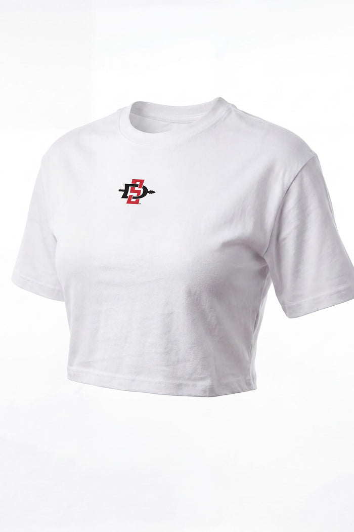 A white short-sleeve cropped t-shirt with a small red and black graphic logo on the left chest, displayed on a clean white background.
