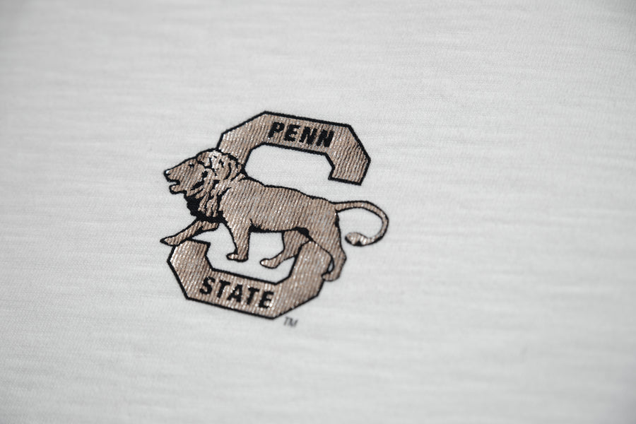 A close-up of a white textured fabric featuring an embroidered Penn State logo with a lion and the words 'PENN STATE'.